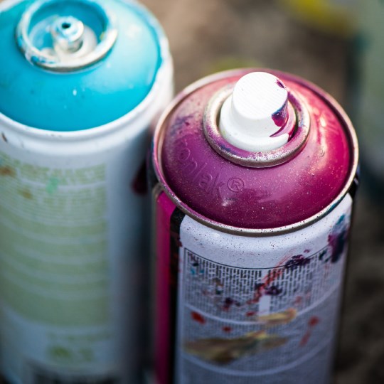 two spray cans with paint on cans blue and pink